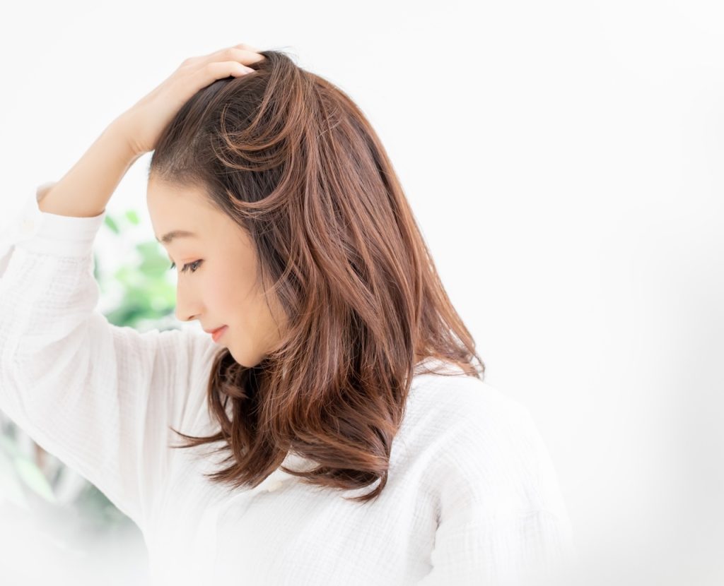 髪をかきあげる女性 | 株式会社ワンウェーブジャパン